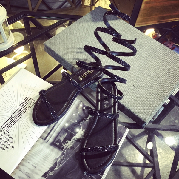 Οι γυναίκες σανδάλια με λουριά στα πόδια σε ασημί και μαύρο γυαλιστερό χρώμα