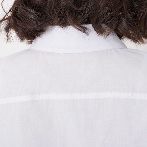 σύντομο βαμβακερά πουκάμισα των γυναικών το καλοκαίρι σε λευκό
