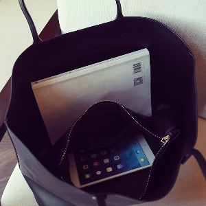 Голяма черна чанта с целувка и малко портмоне тип несесер вътре в нея, удобна за ежедневие или пътуване