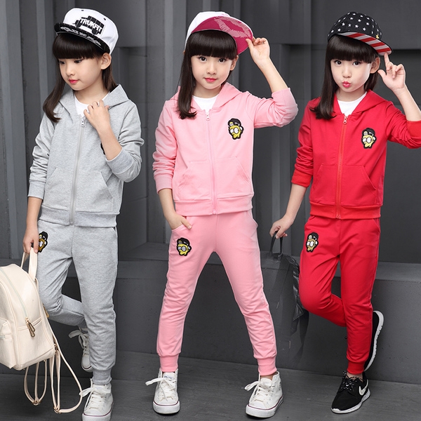 Παιδικά αθλητικά σύνολα για κορίτσια σε τρία μέρη: Φούτερ, μπλούζα και παντελόνια σε γκρι, ροζ και κόκκινο χρώμα.